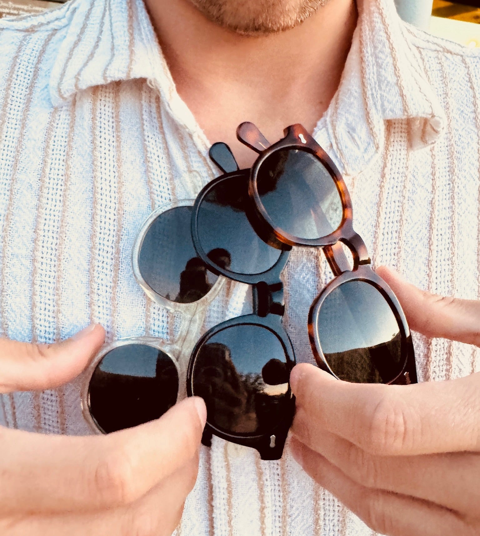 3 pairs of "Macchiatos" sunglasses hanging on a model's shirt collar